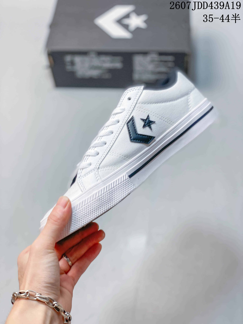 Side profile of the white low-top sneaker with its dark star-and-chevron emblem, white midsole, and textured outsole.