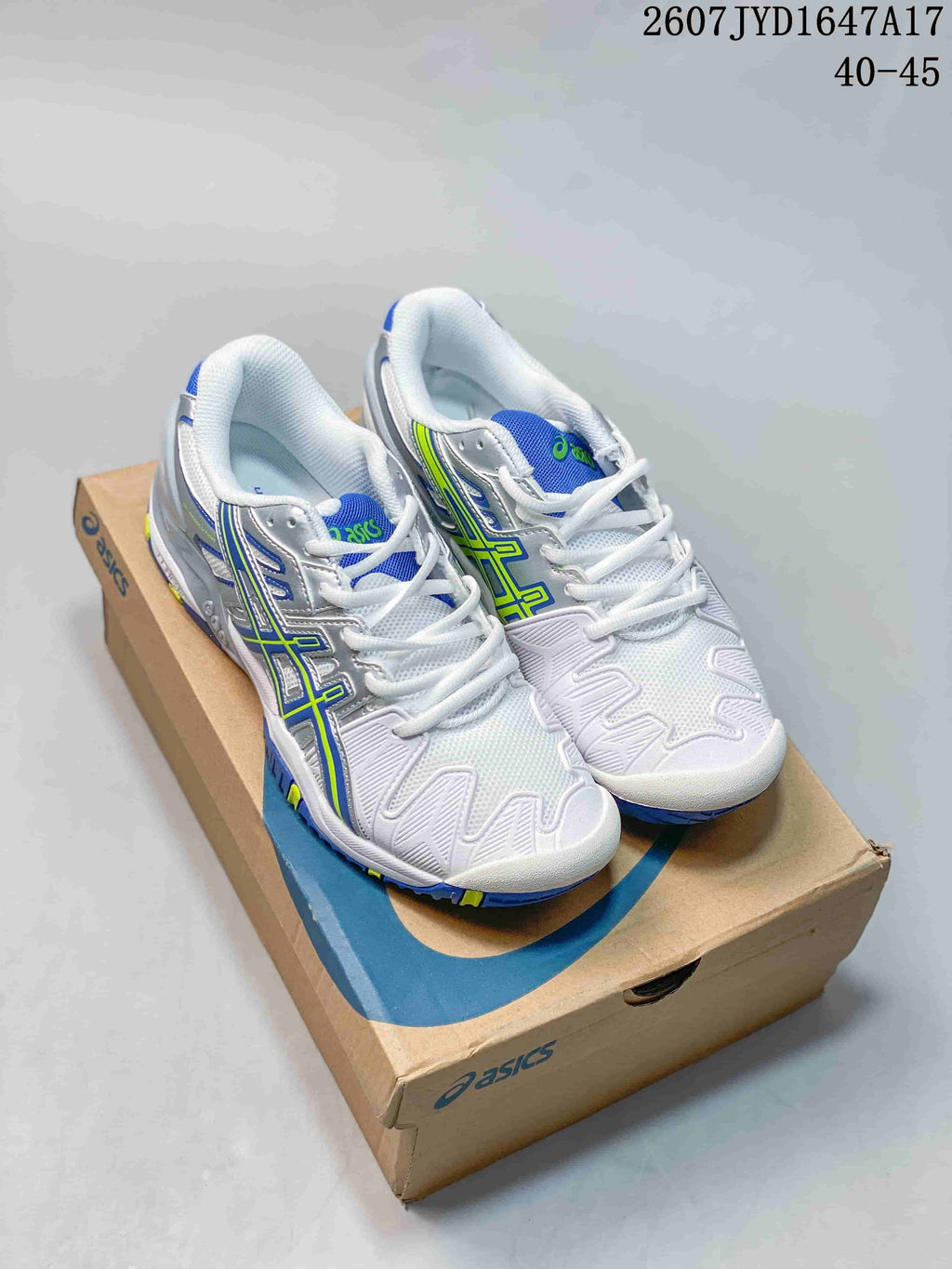Pair of white ASICS GEL-Resolution 5 tennis shoes with blue and neon yellow accents displayed on an ASICS shoe box; image text shows style code 2607 TYD1647A17 and EU size range 40–45.