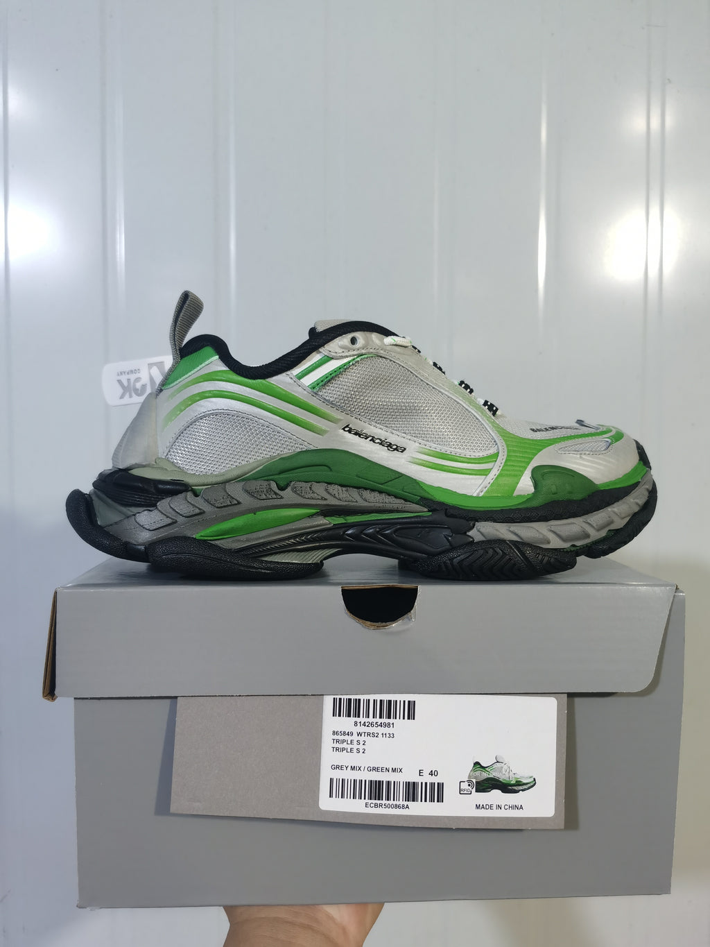 Side profile of the grey and green sneaker displayed on its box; the label shows Triple S 2, WTRS 1133, GREY MIX / GREEN MIX, and E 40.