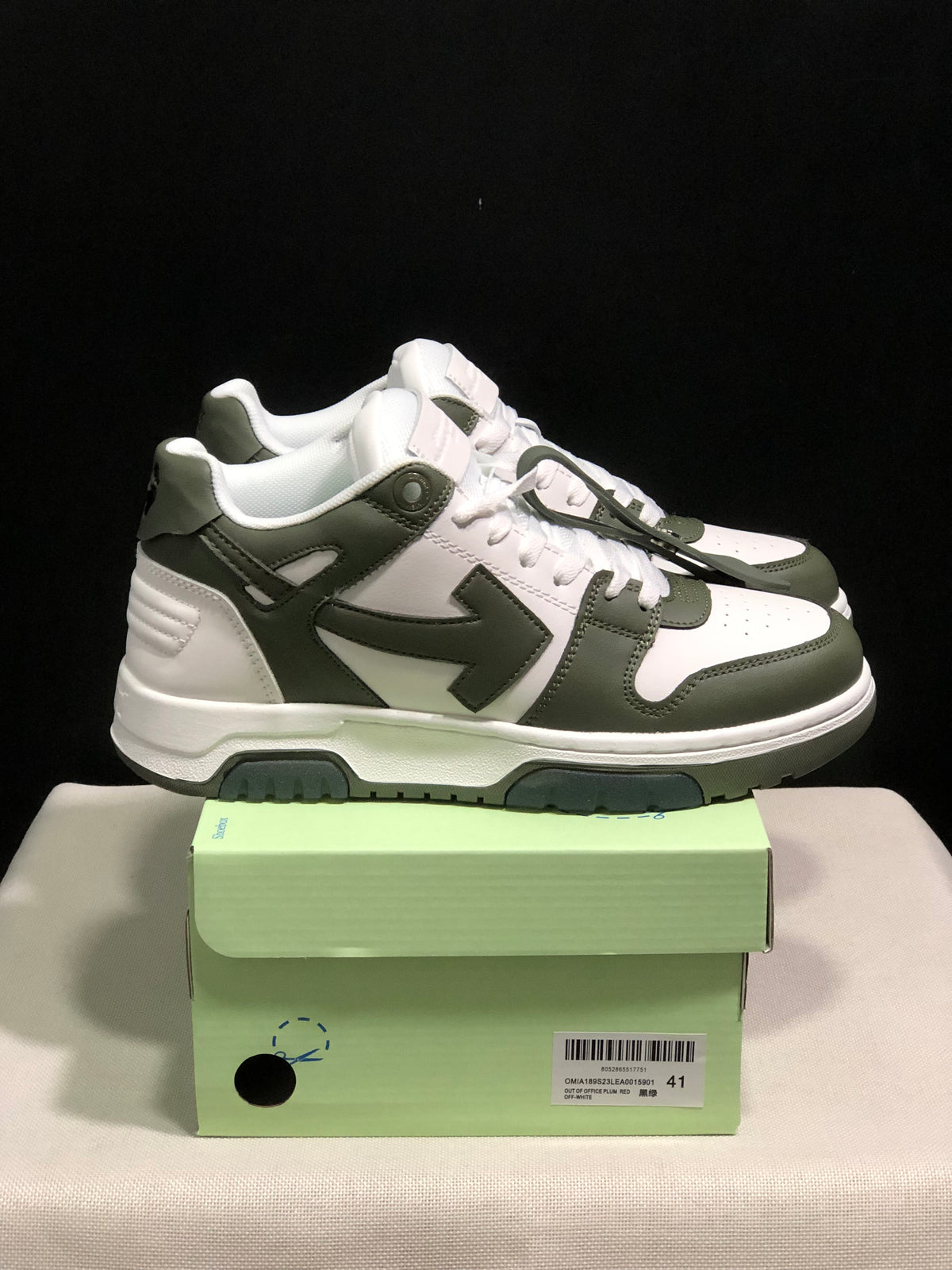 Side view of the white and olive low-top sneakers with contrast overlays and green outsole accents.
