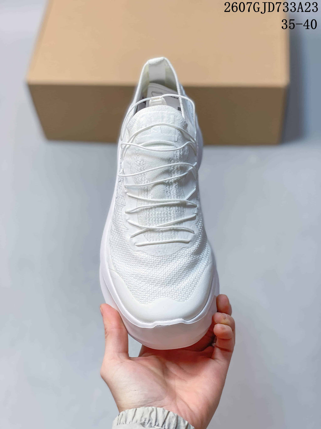 Front view of the white sneaker showing the layered lace arrangement and textured upper.