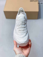 Front view of the white sneaker showing the layered lace arrangement and textured upper.