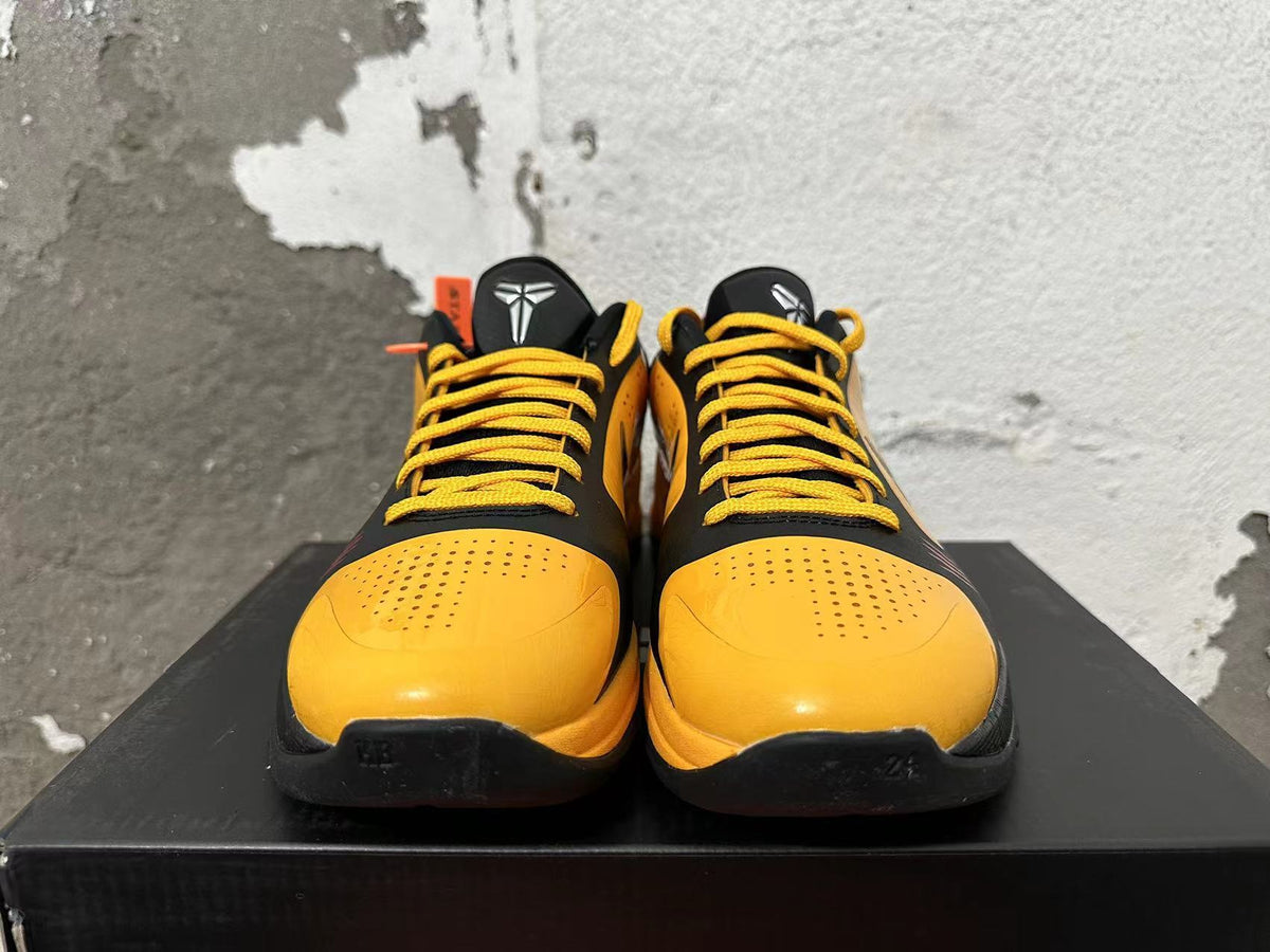 Front view of black and yellow low-top basketball shoes with yellow laces and perforated toe boxes