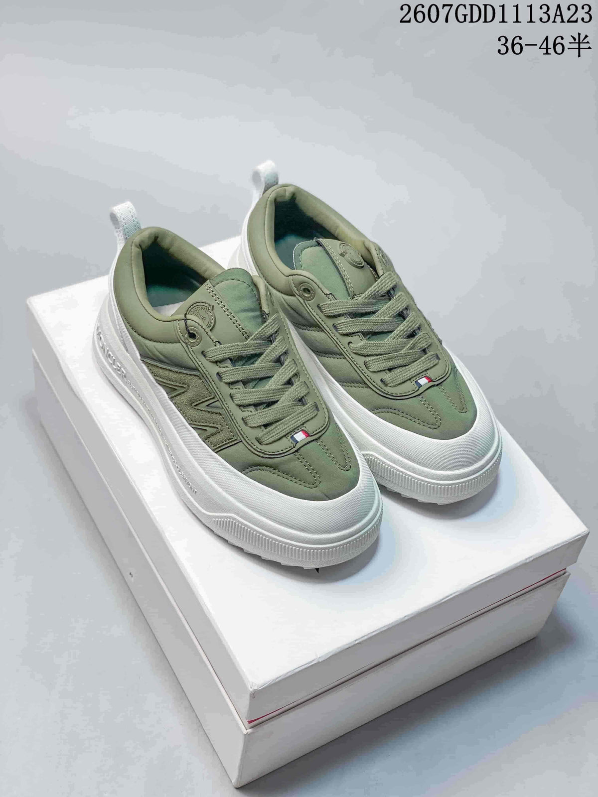 Pair of muted green Moncler Pacey low-top sneakers with white chunky soles displayed on a shoebox.