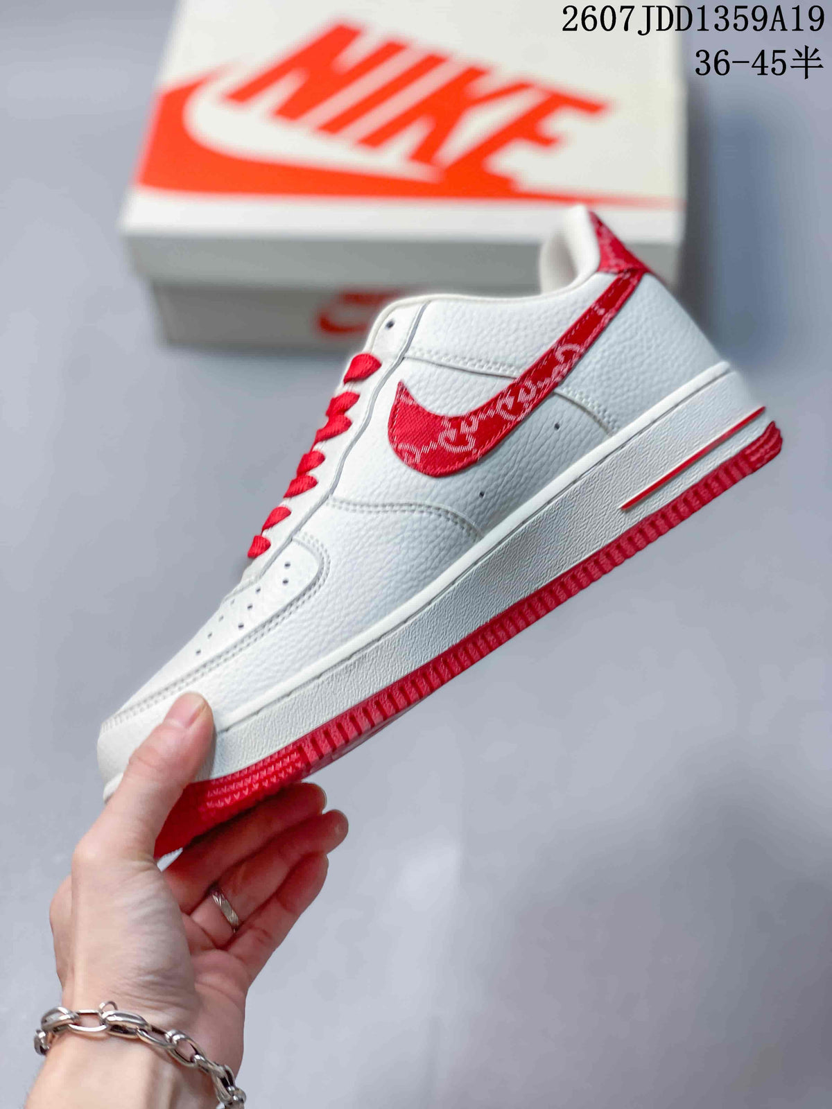 Side profile of the white low-top sneaker showing the red patterned Swoosh-style panel and red outsole.