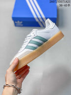 Side profile showing the white upper, mint-green three stripes, gray toe detailing, and gum sole.