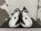 Front view of white-and-black Nike basketball shoes with white laces and gold trim.
