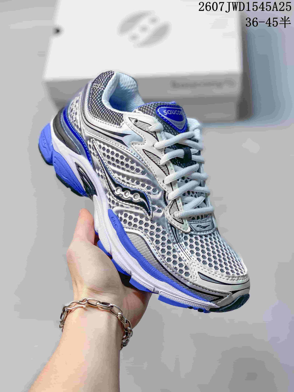 Angled side view of a Saucony ProGrid Omni 9 sneaker showing the white, gray and blue upper and layered sole.