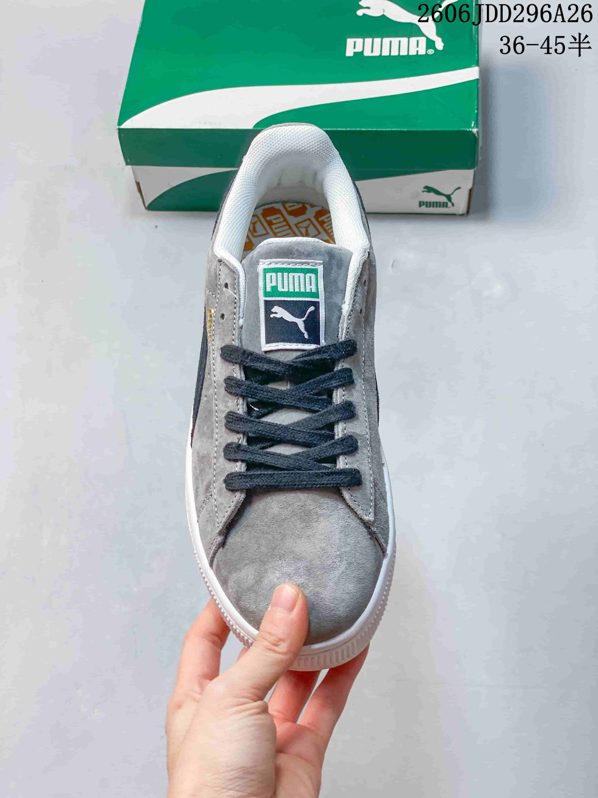 Top view of a gray lace-up Puma sneaker showing the tongue label, dark navy laces and white padded collar.