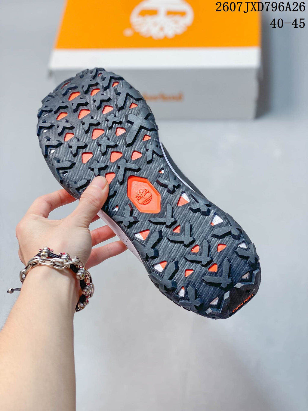 Close view of the dark lugged outsole with orange openings and a Timberland tree emblem.