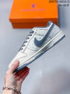 Side profile showing the white and grey upper, dark grey Swoosh, printed monogram-style panels, and layered sole.