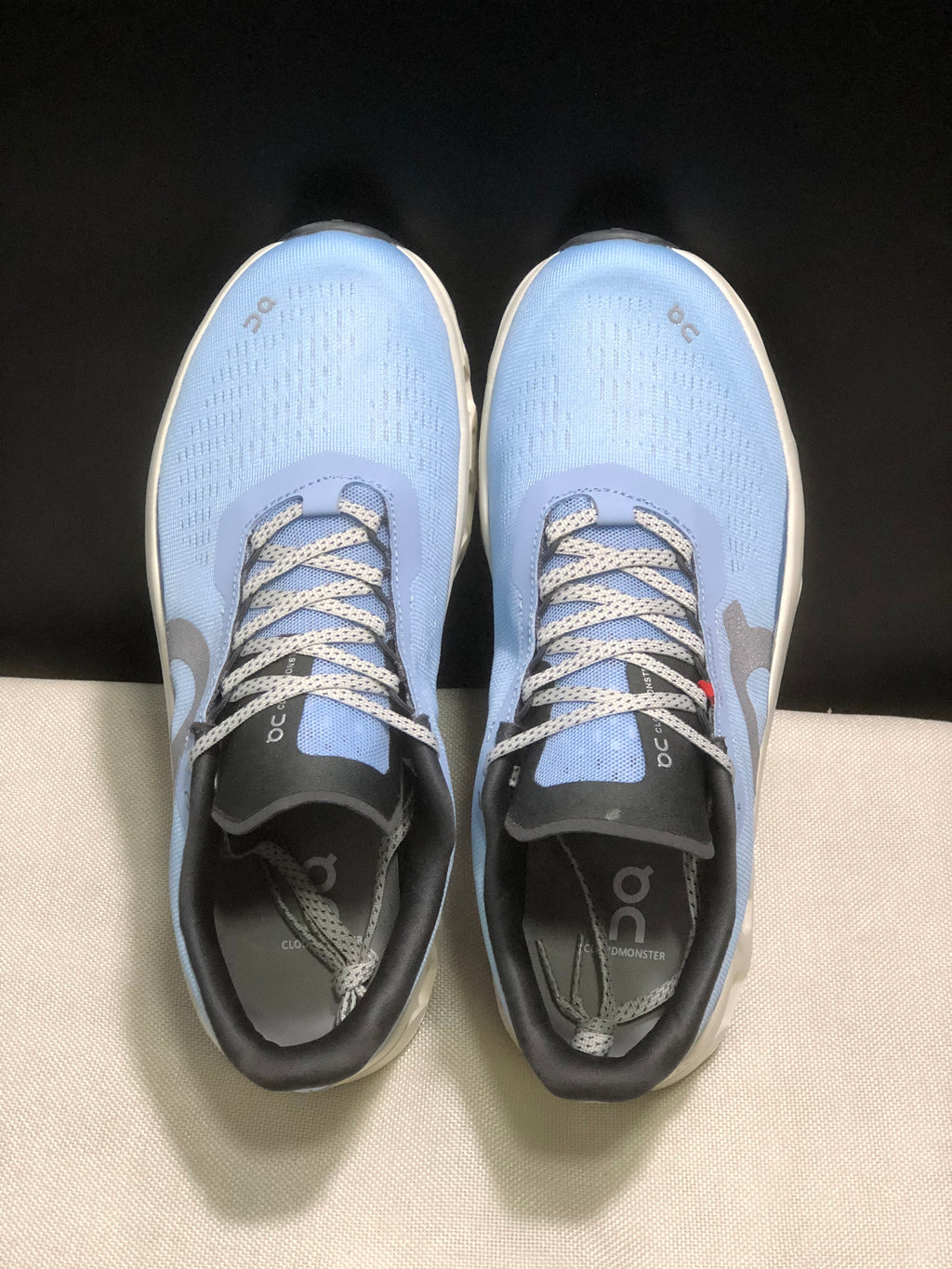Top view showing the light blue uppers, patterned laces, black tongues, and branded insoles.