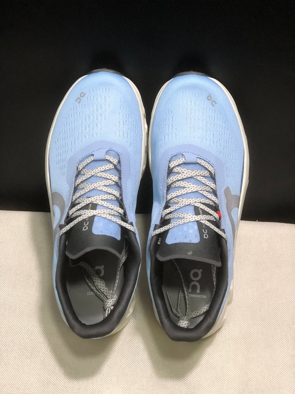 Top view showing the light blue uppers, patterned laces, black tongues, and branded insoles.