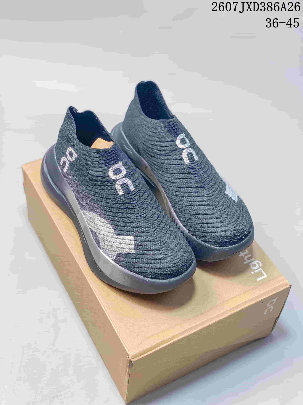 Pair of dark gray On slip-on sneakers displayed on a branded shoebox.