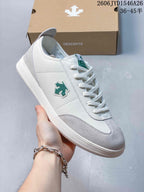 Close-up of a white and pale gray sneaker with green side emblem