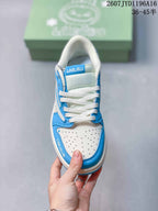 Top view of the sneaker showing white laces, a perforated white toe box, blue overlays, and Labubu tongue branding.