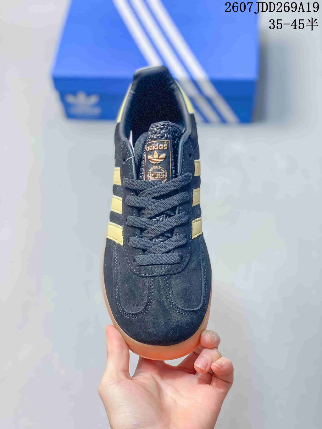 Top view showing the black lace-up sneaker, padded collar, tongue branding, and gold side stripes.
