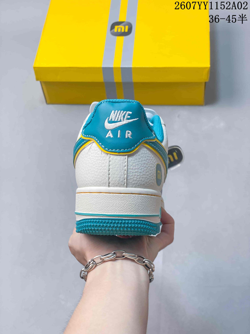 Rear view of the sneaker showing turquoise heel details and white upper