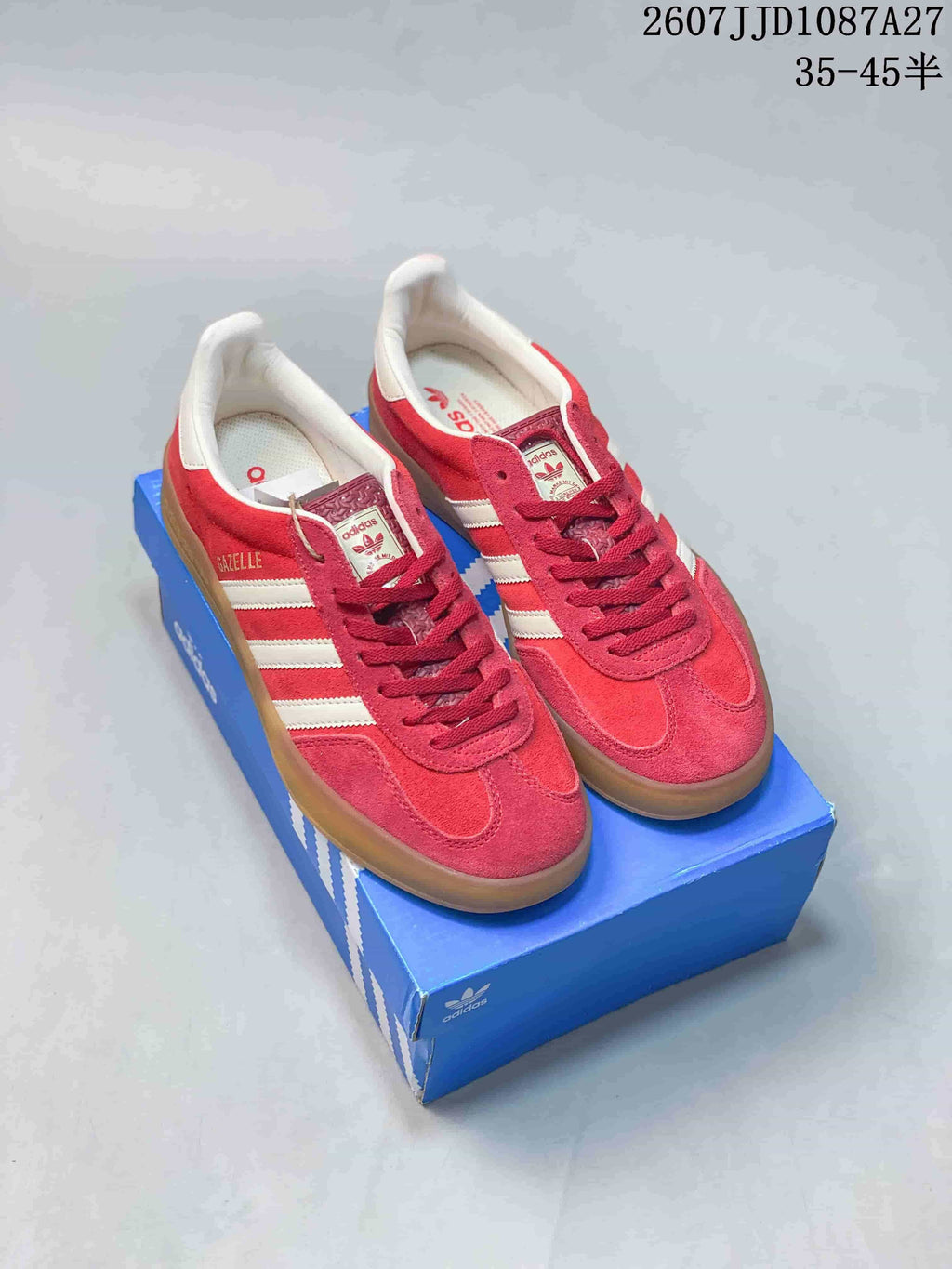 Pair of red and white adidas low-top sneakers displayed on a blue shoebox; overlay text shows style code 2607JJD1087A27 and size range 35–45 with half sizes.