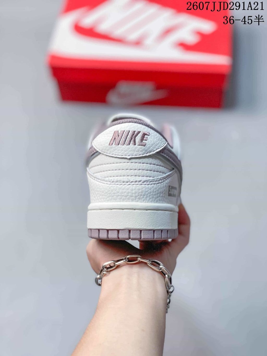 Rear view of the sneaker showing the padded heel, heel branding, white midsole, and muted gray outsole.