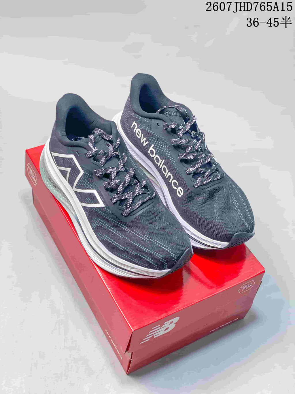 Pair of dark gray and white New Balance RC Elite running shoes displayed on a red shoebox.