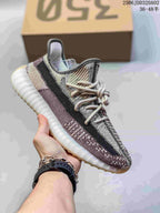 Light gray and beige knit sneaker with a black side stripe, light laces, and a white ribbed sole.