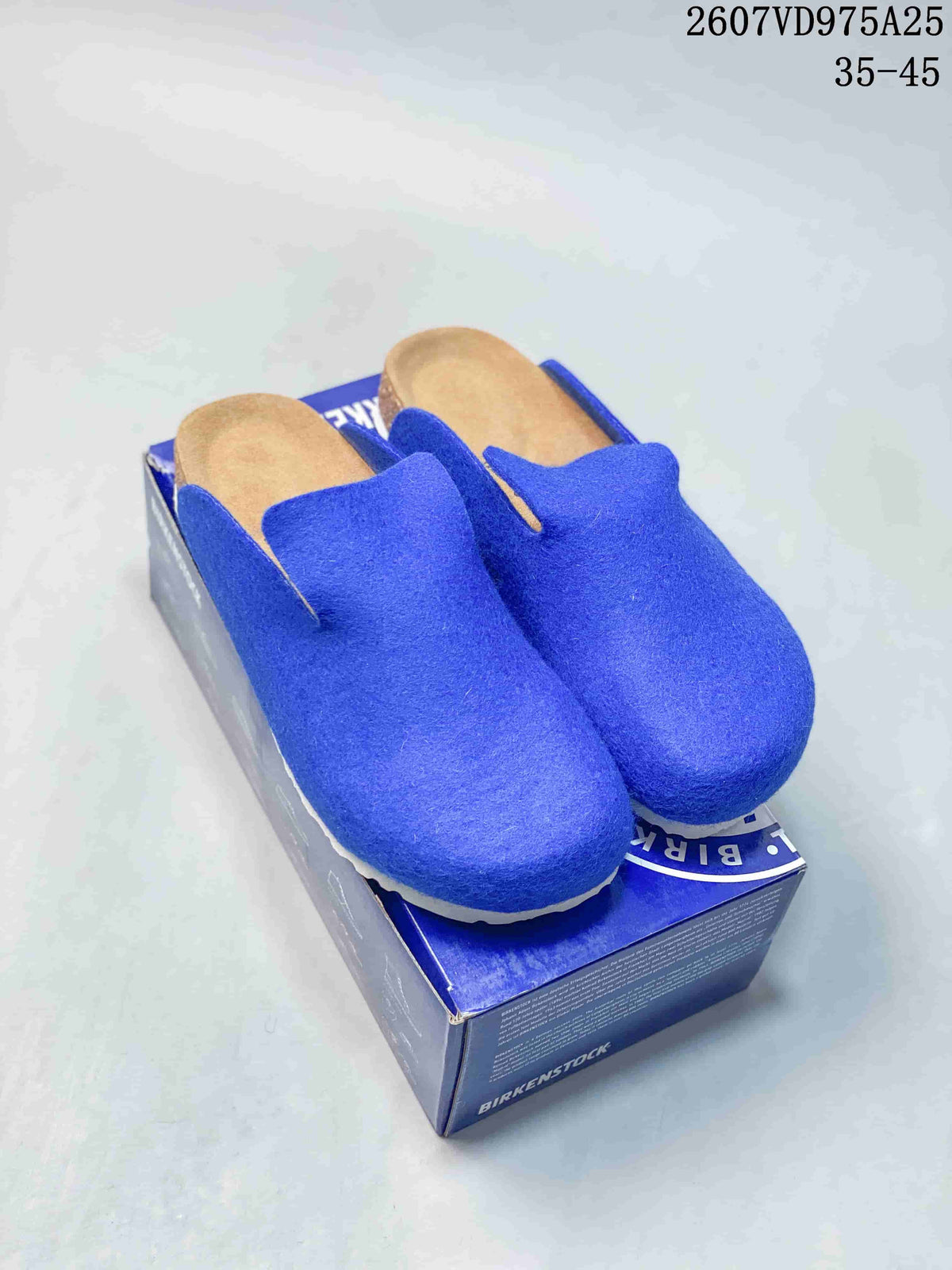 Pair of blue Birkenstock Amsterdam clogs displayed on a blue shoebox, with the tan footbed and white outsole visible.