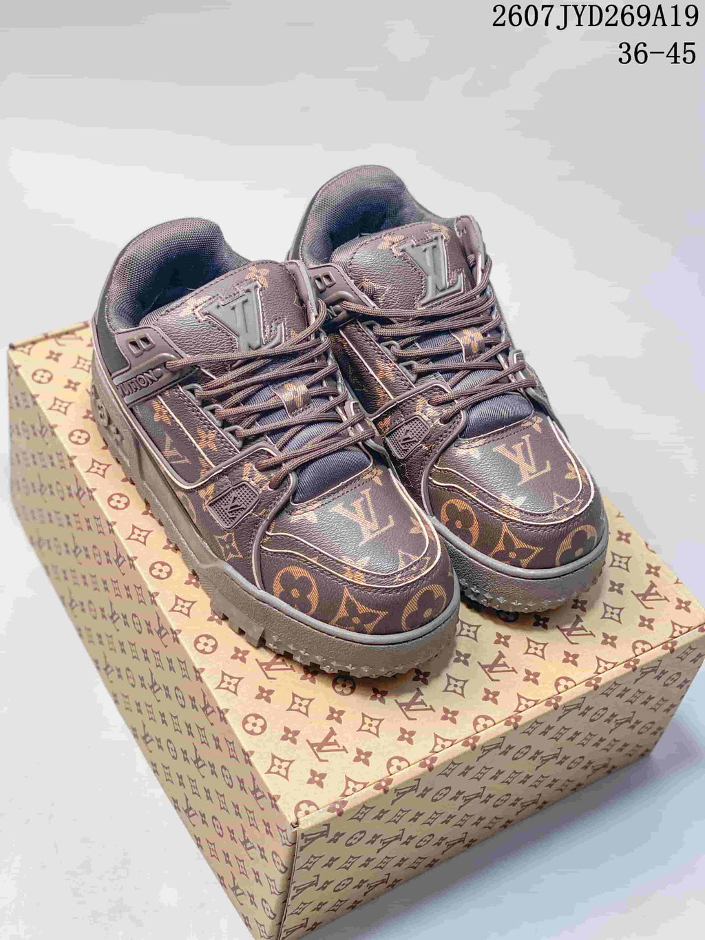 Pair of brown Louis Vuitton Trainer Maxi sneakers displayed on a patterned shoe box; the image shows the style code text and size range 36–45.