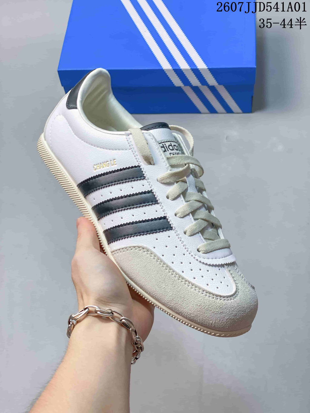 Angled view of the white sneaker with dark stripes and textured toe overlay