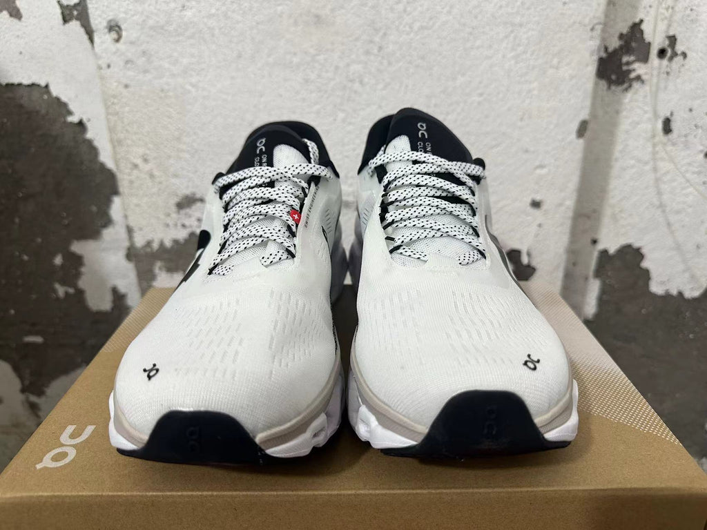 Front view of white On Running sneakers with black-and-white laces and black accents