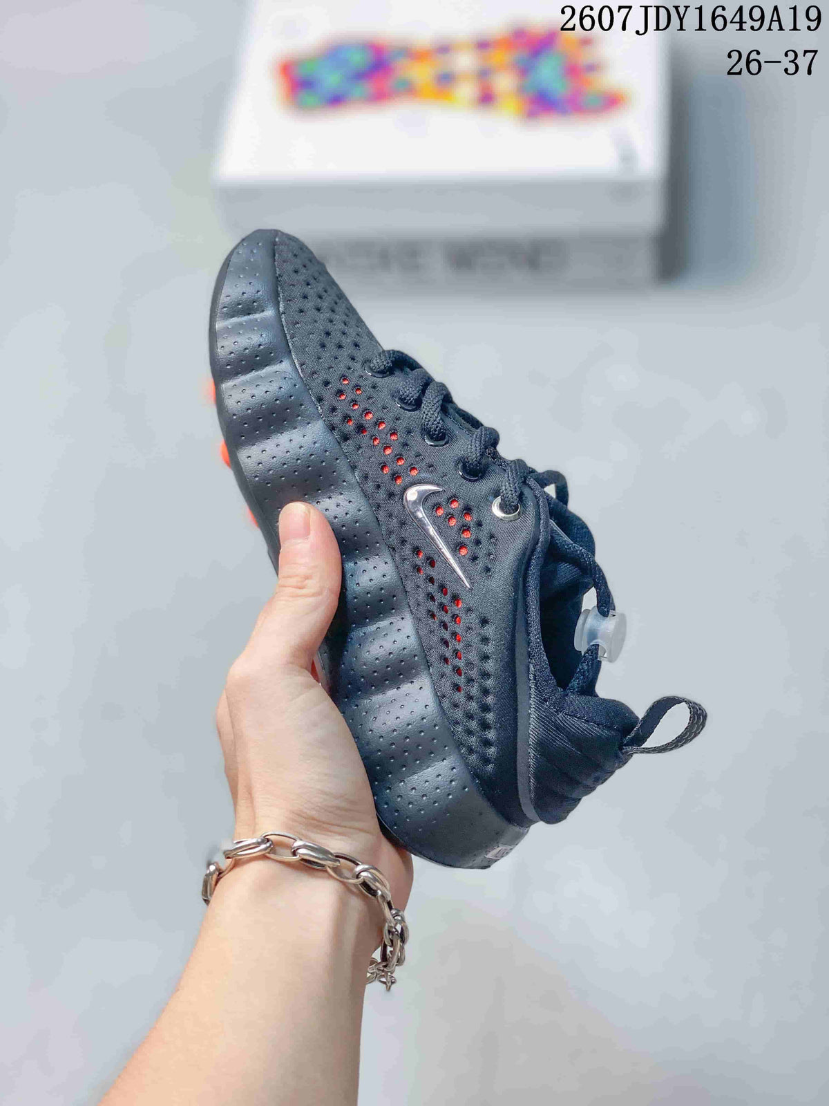 Side view of the black sneaker showing the perforated upper, Nike Swoosh, lace eyelets, and segmented sole.