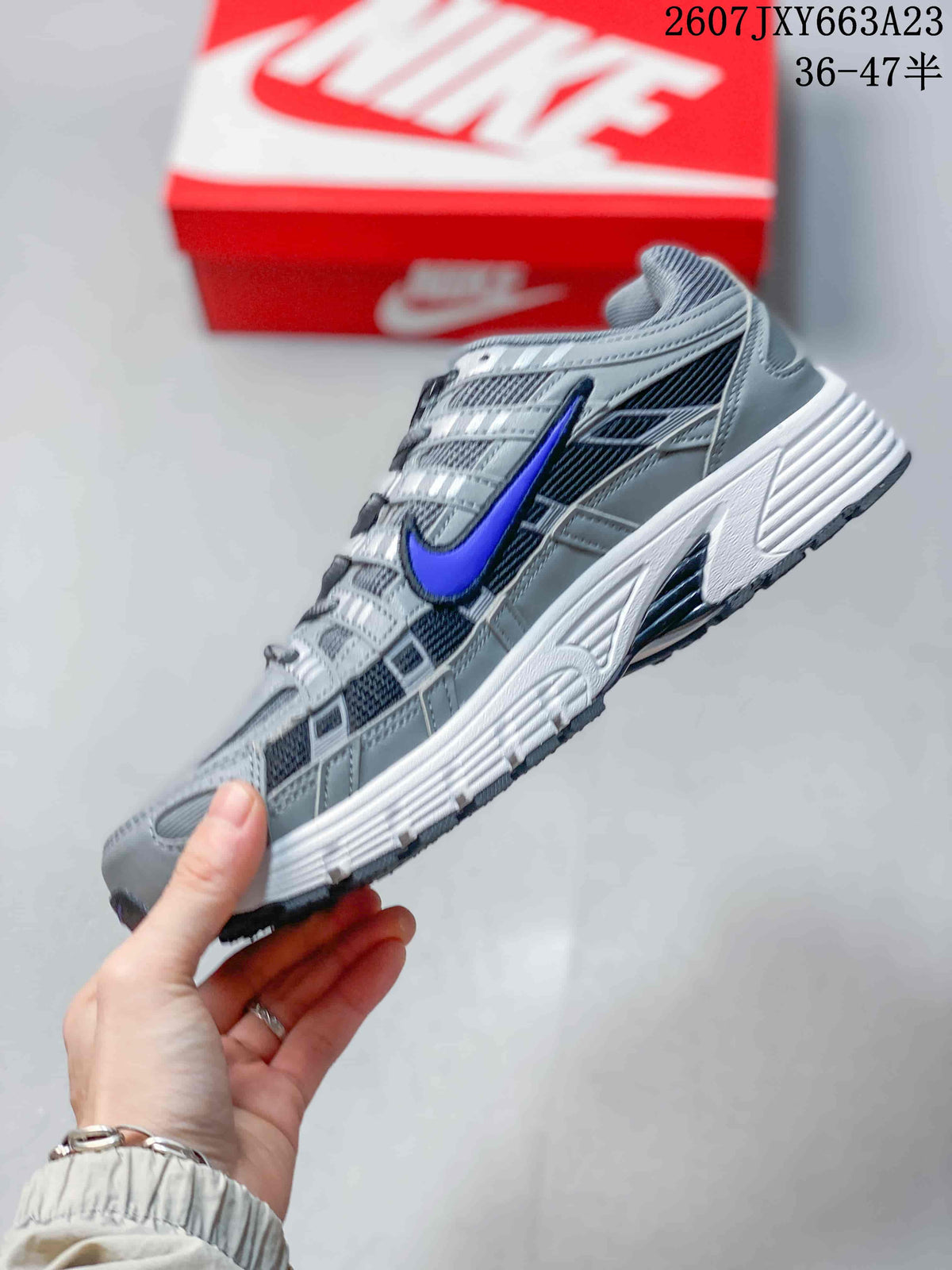 Side profile of the gray and blue Nike P-6000 showing mesh-style panels, overlays, and a textured sole.