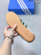 Close view of the gum-colored outsole with adidas branding on a white and green sneaker.