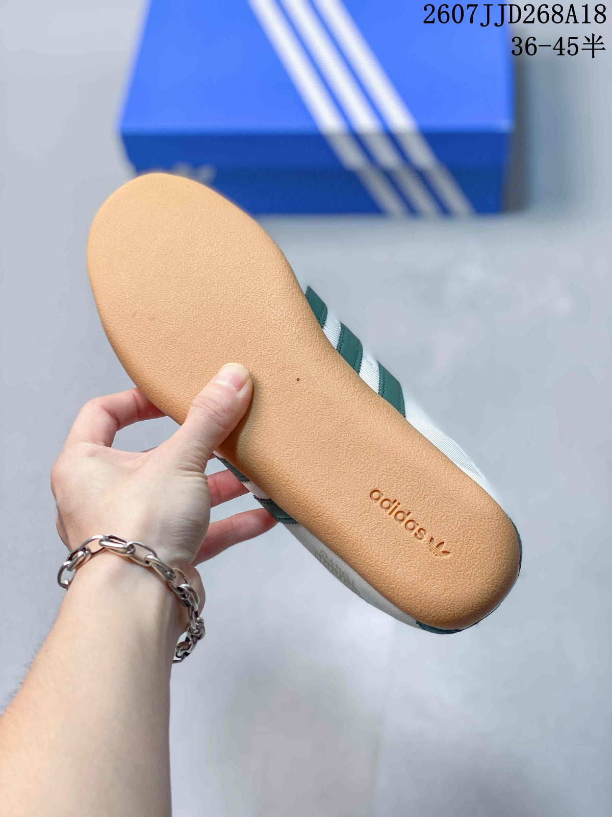 Close view of the gum-colored outsole with adidas branding on a white and green sneaker.