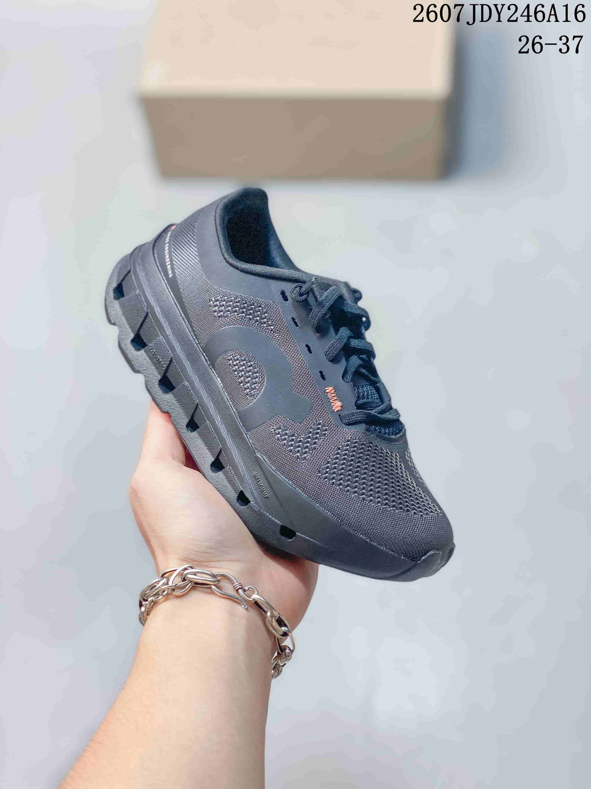 Side three-quarter view of the dark gray sneaker showing the patterned upper panels and segmented outsole.