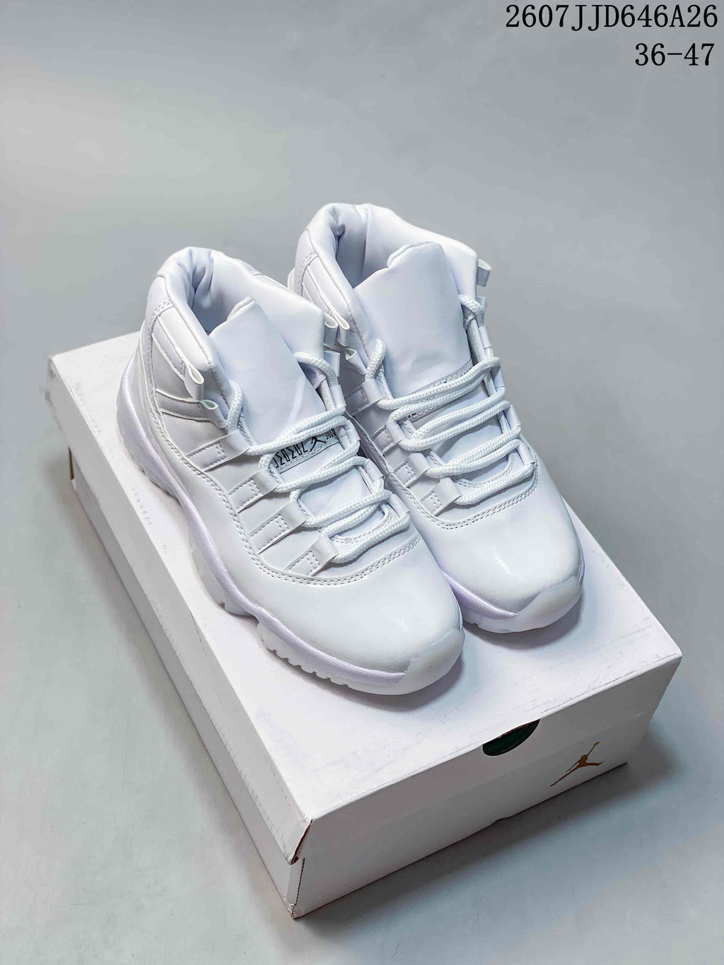 Pair of white Jordan Air Jordan 11 Retro high-top sneakers displayed on a shoebox; source overlay shows style code 2607JJD646A26 and size range 36–47.