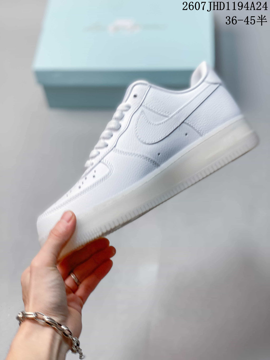 Side profile of a white low-top sneaker showing the layered panels, Swoosh and translucent outsole.
