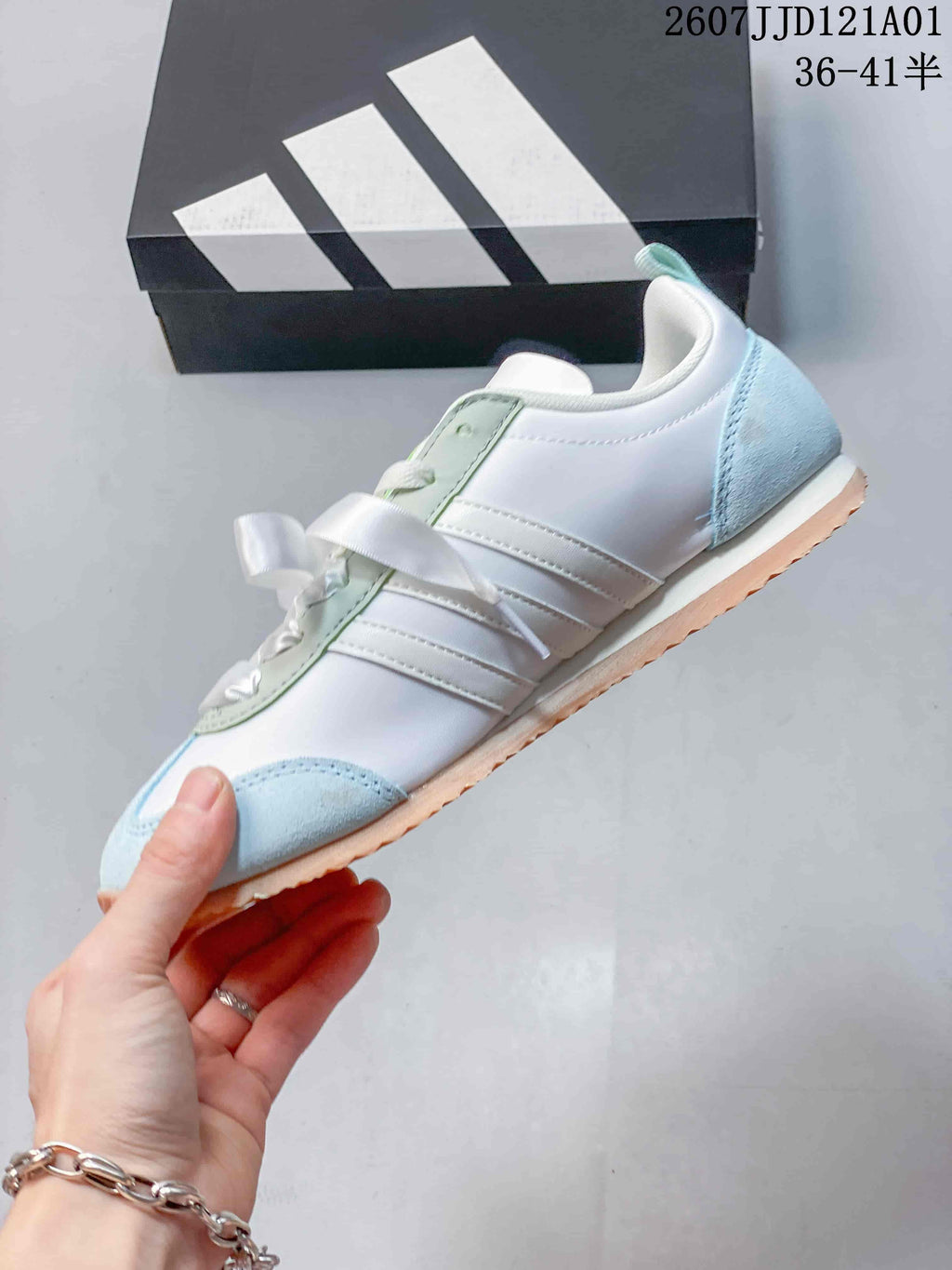 Side profile of a white and pale blue adidas JOG 2.0 sneaker with three stripes