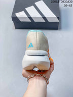 Rear view of a beige running shoe with a turquoise Adidas mark and sculpted white heel