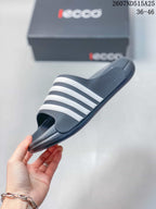 Side view of a dark slide sandal with four white bands, a raised footbed, and a molded outsole.