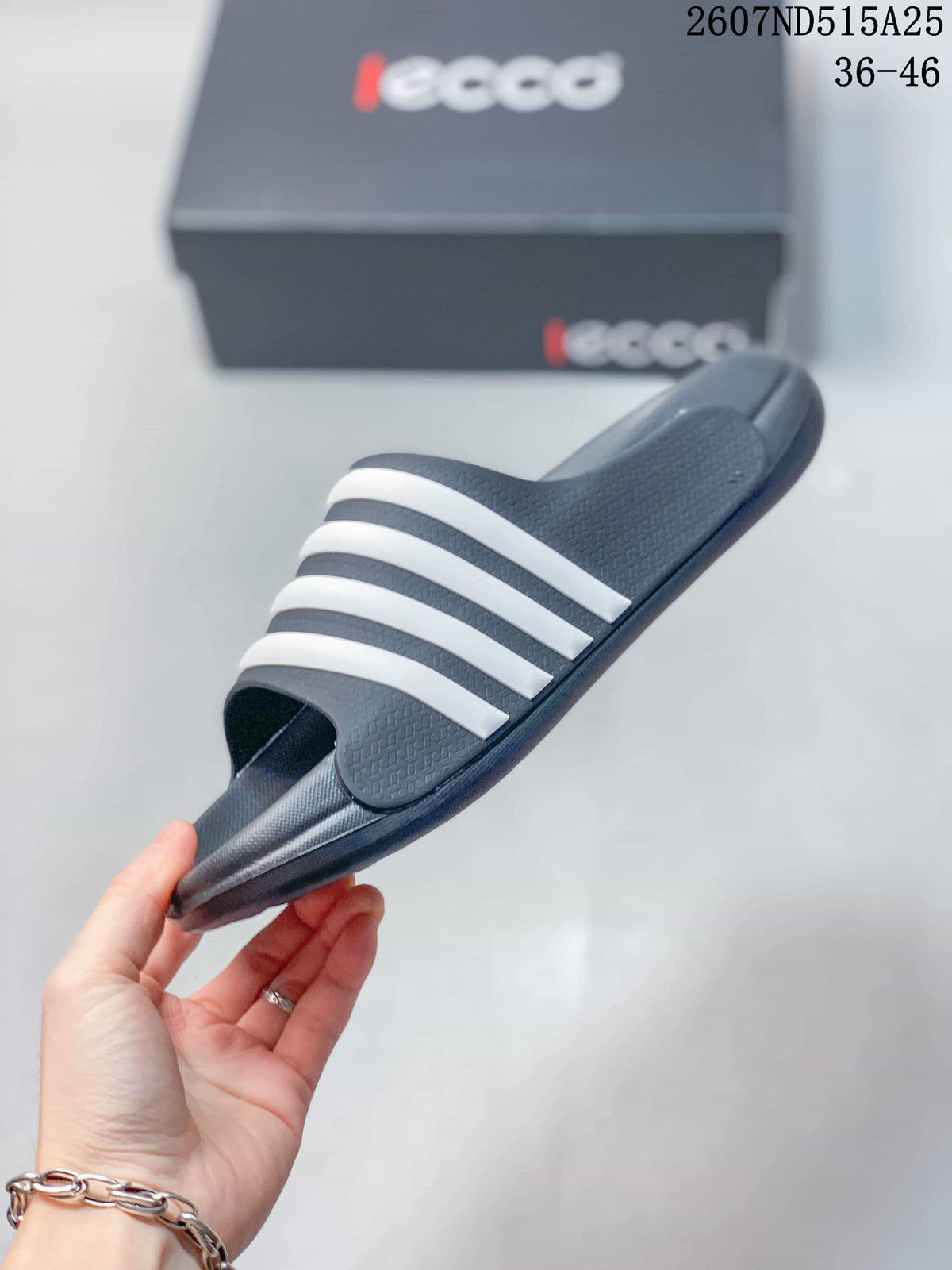 Side view of a dark slide sandal with four white bands, a raised footbed, and a molded outsole.