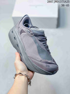Angled side view of the gray sneaker showing the layered upper, mesh section, lace system, and sculpted sole.