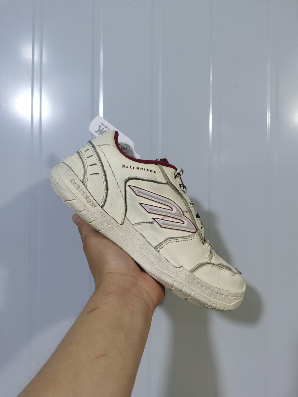 Angled view of the off-white and red Balenciaga Hamptons sneaker showing the layered upper, side logo and lace-up front.