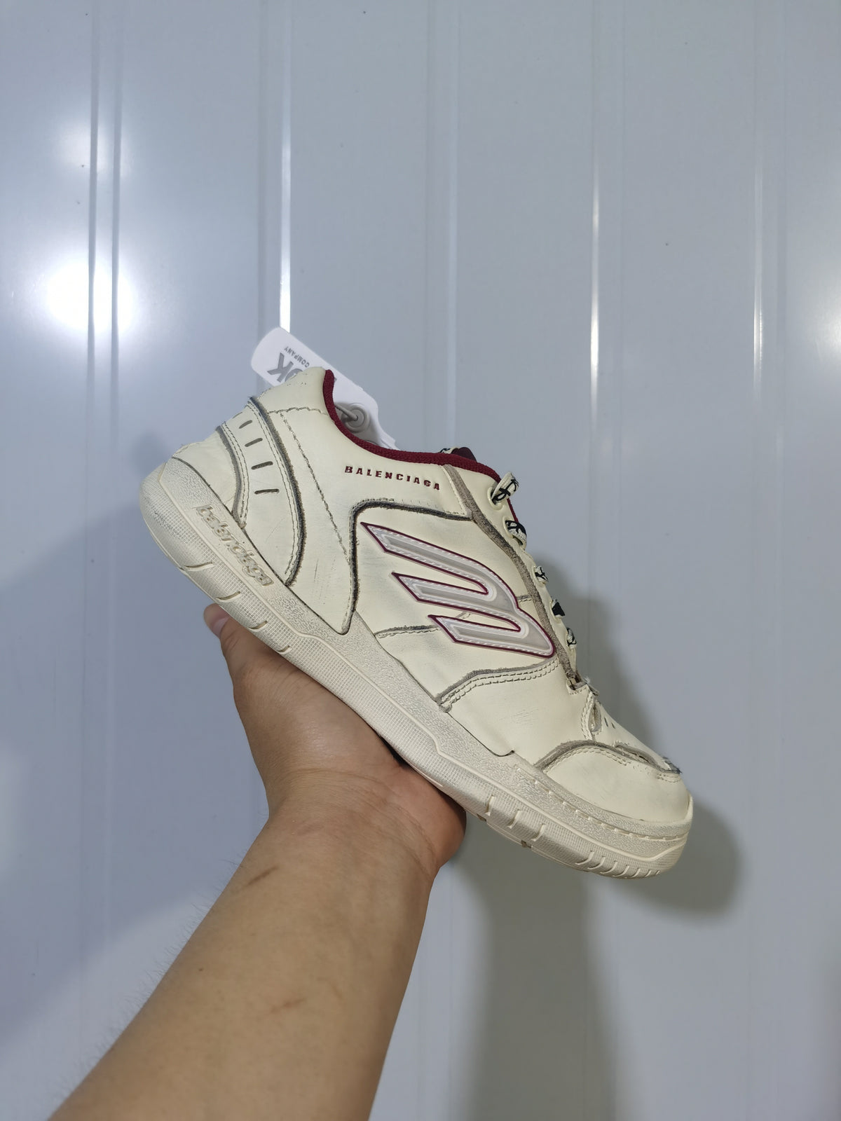 Angled view of the off-white and red Balenciaga Hamptons sneaker showing the layered upper, side logo and lace-up front.