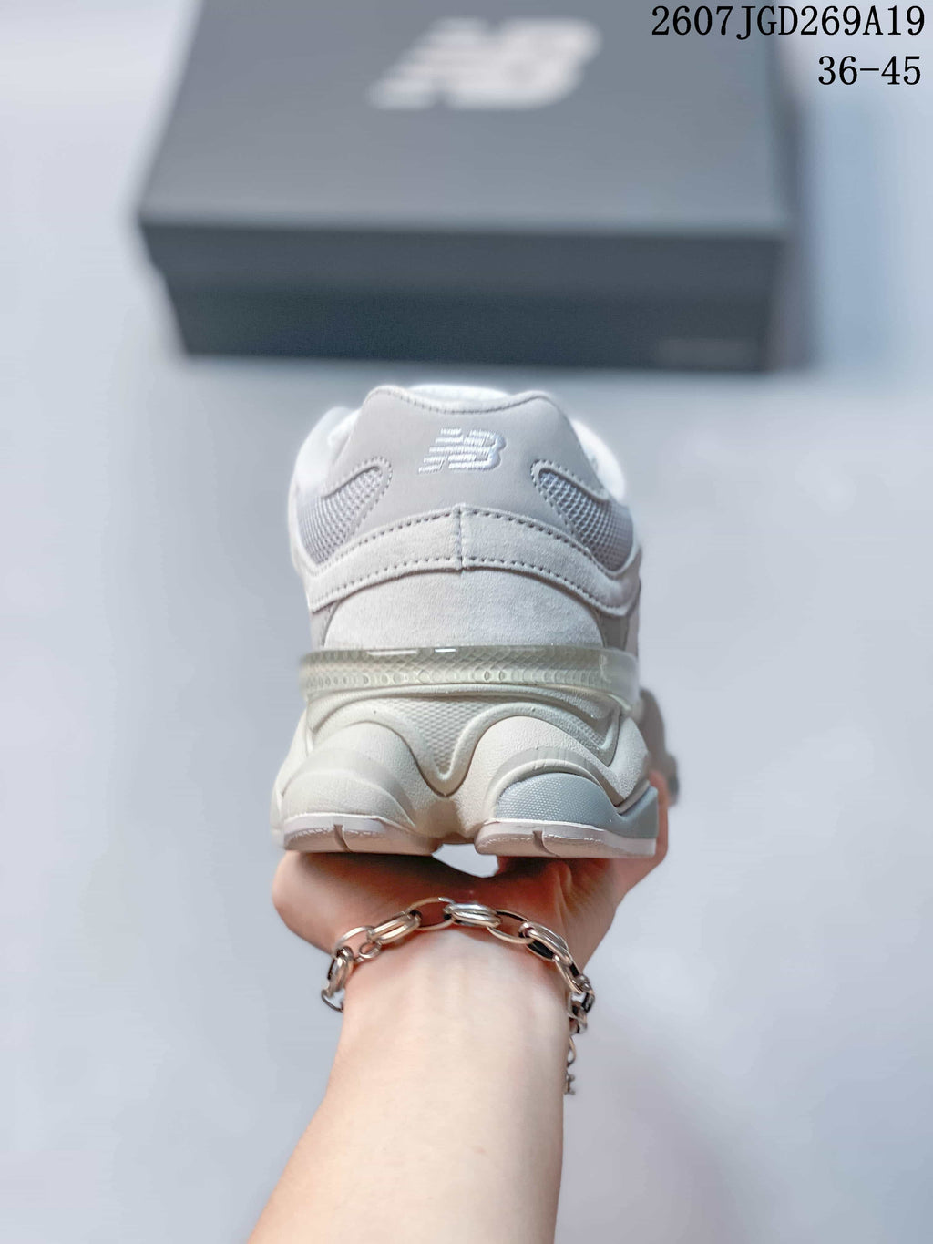 Rear view of a light white New Balance 9060 sneaker showing the padded heel collar, layered heel structure and New Balance logo.