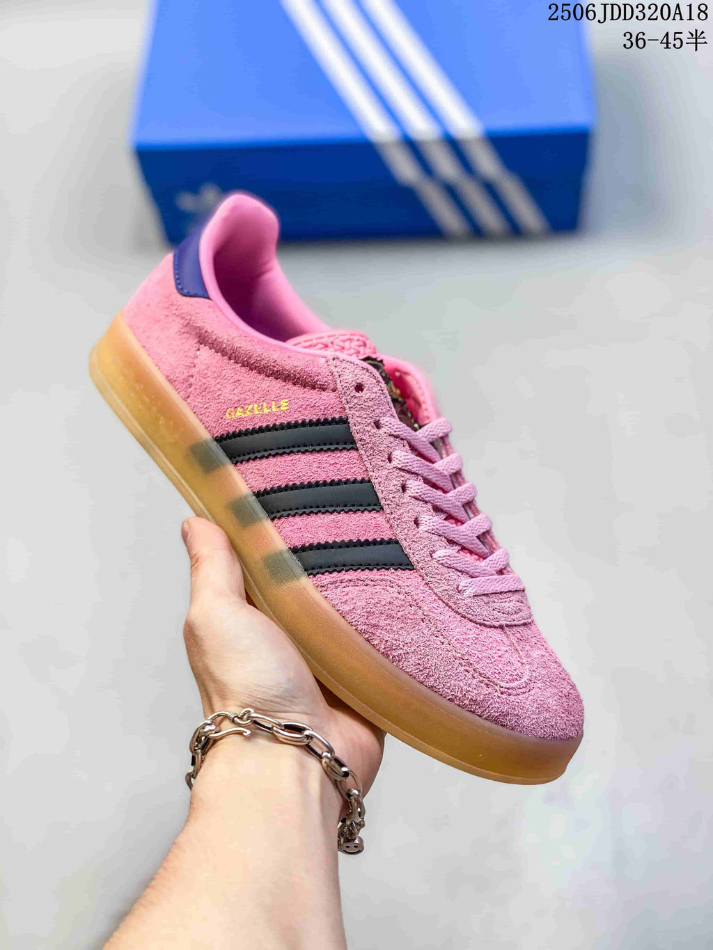 Angled side view showing the pink Adidas Gazelle sneaker, black stripes, gum-colored sole and visible Gazelle side text.