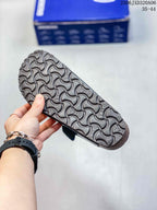 Bottom view of a black clog showing the repeating textured outsole tread.