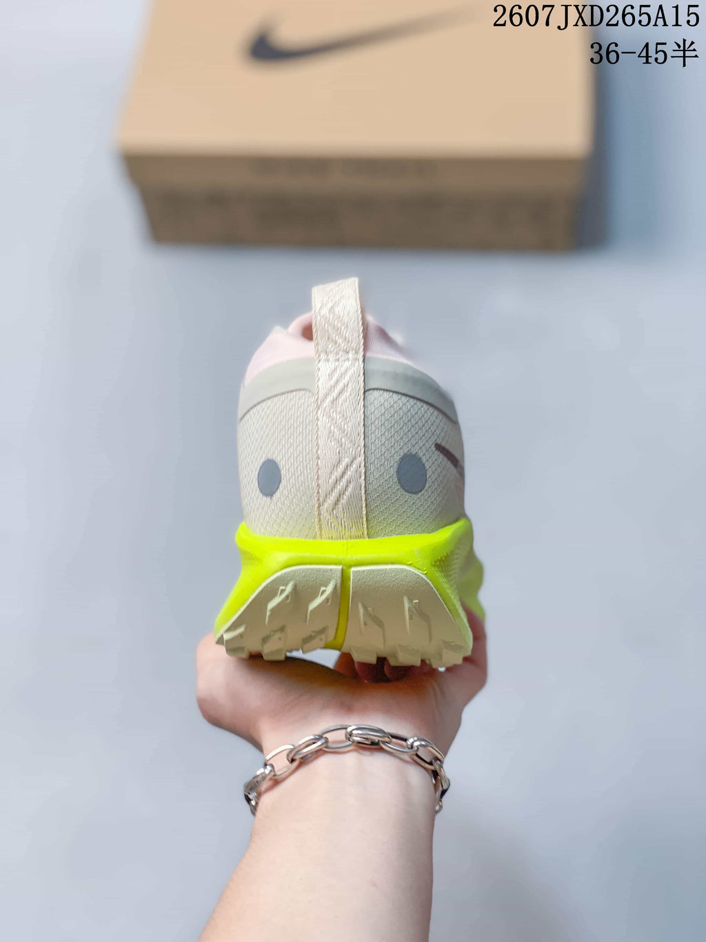 Rear view of the sneaker showing the heel pull tab, light gray textile upper, pink lining, and neon yellow outsole edge.