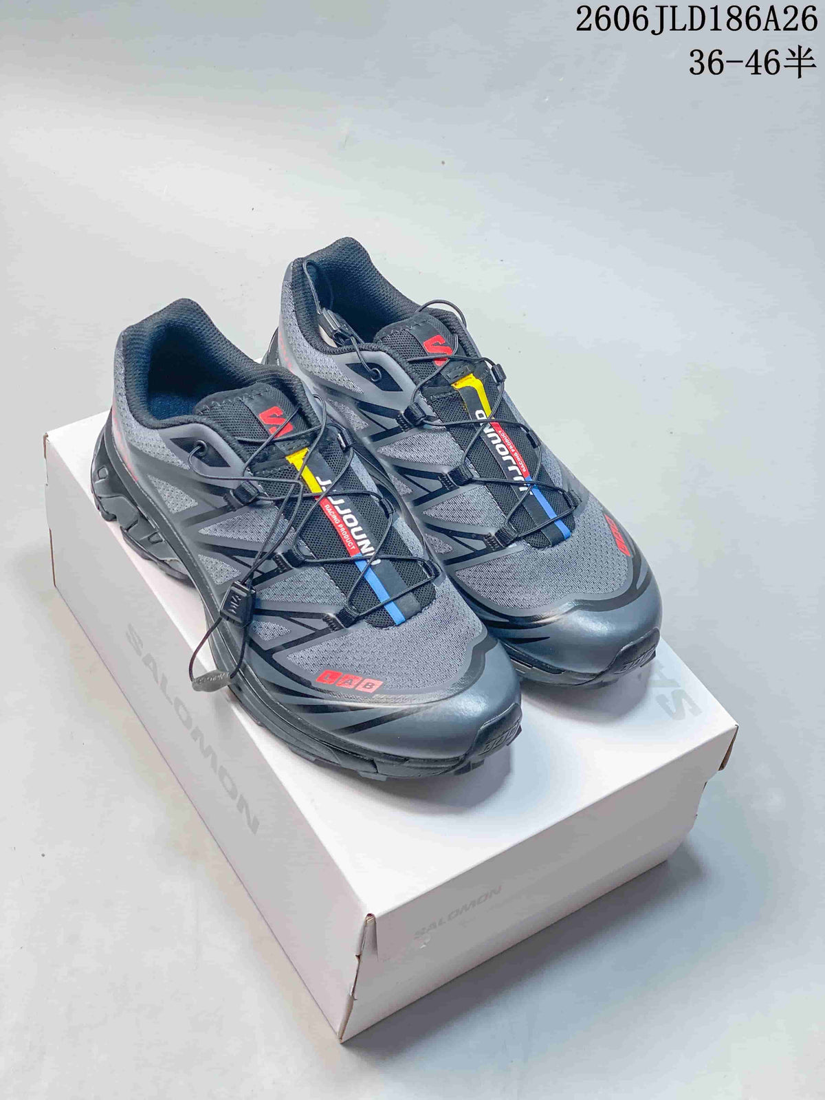 Pair of gray Salomon XT-6 shoes with quick laces and colored accents, shown on a shoe box