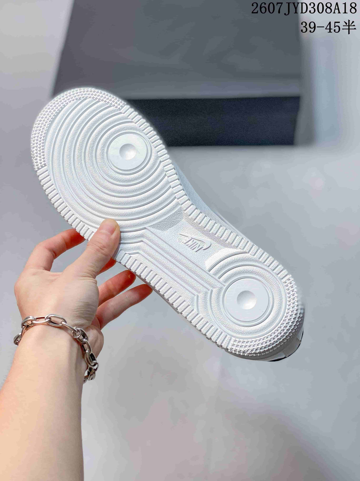 View of the white textured outsole with circular traction patterns and raised branding details.